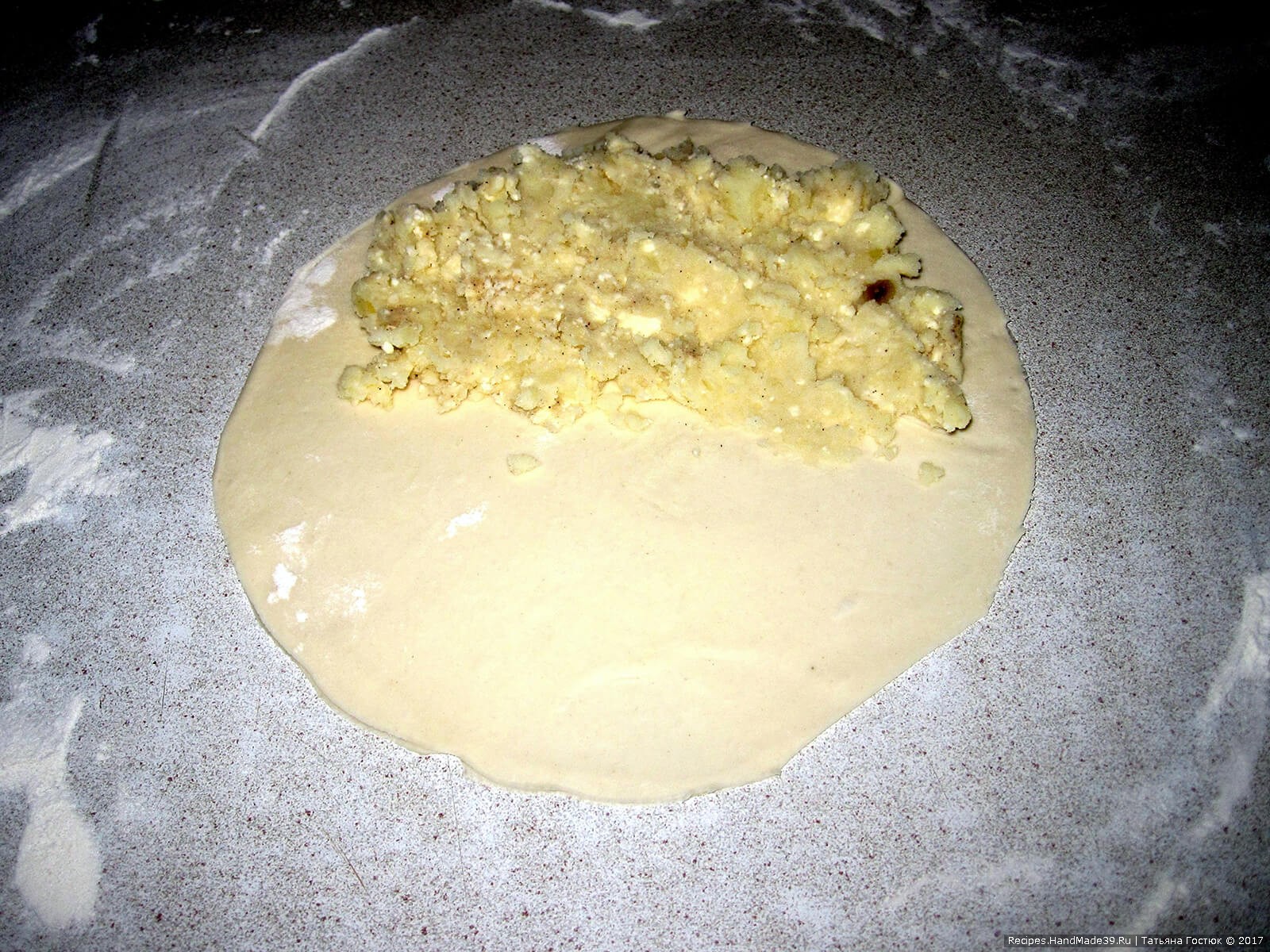 На половинку круга выкладываем начинку из картофельного пюре и брынзы, слегка придавливая её ложкой или ладонью
