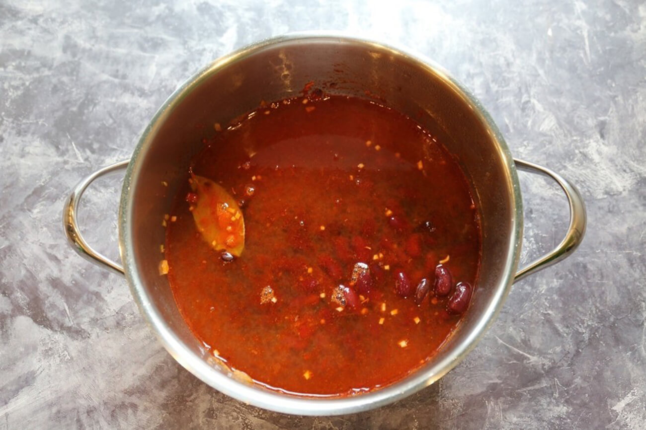Далее влить бульон, добавить фасоль и довести суп до кипения, затем убавить огонь и варить суп 15 минут. В конце посолить и поперчить суп