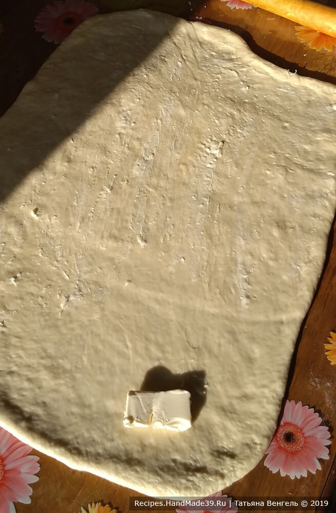 Подошедшее тесто раскатать в прямоугольный пласт толщиной около 5 мм, смазать мягким сливочным маслом