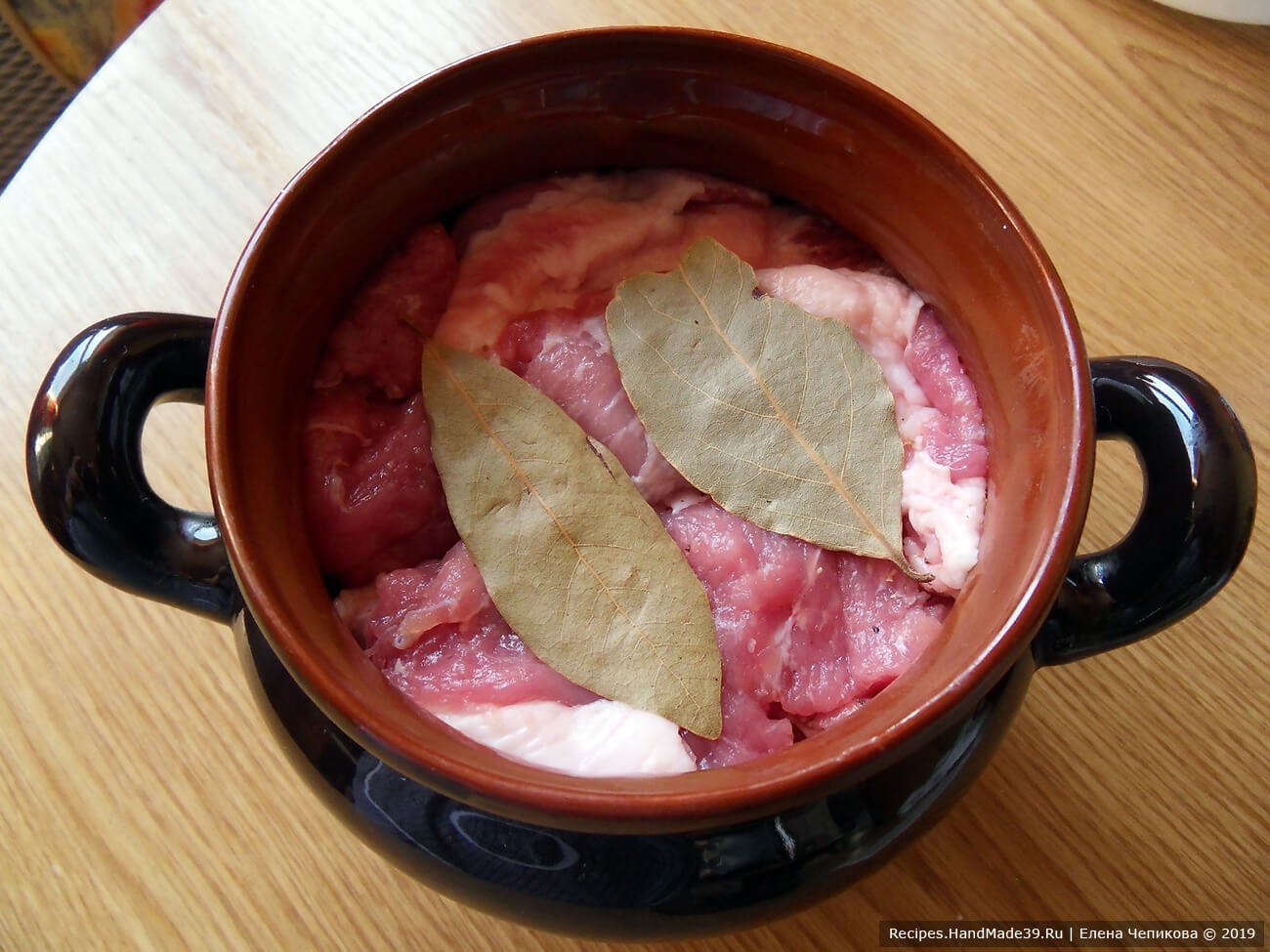 Подготовленное мясо посыпать солью и перцем, перемешать, плотно уложить в ёмкость. Сверху выложить оставшиеся лавровые листы