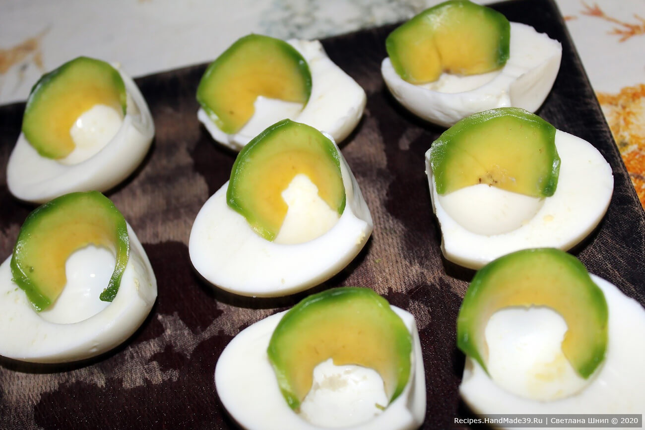 На половинки яиц (белки) выложить по тонкой дольке авокадо